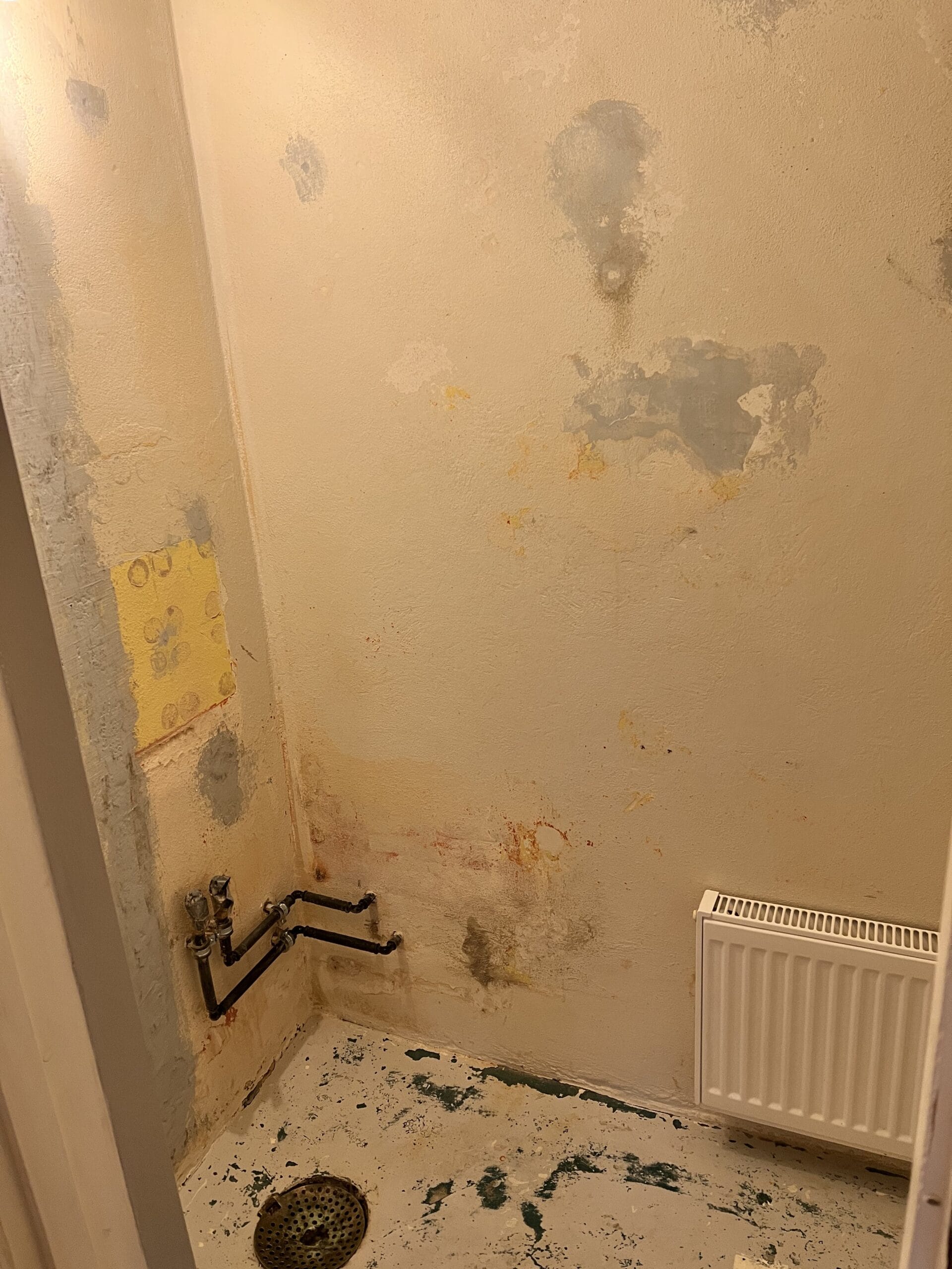 Slidt badeværelse under renovering med afskallet maling