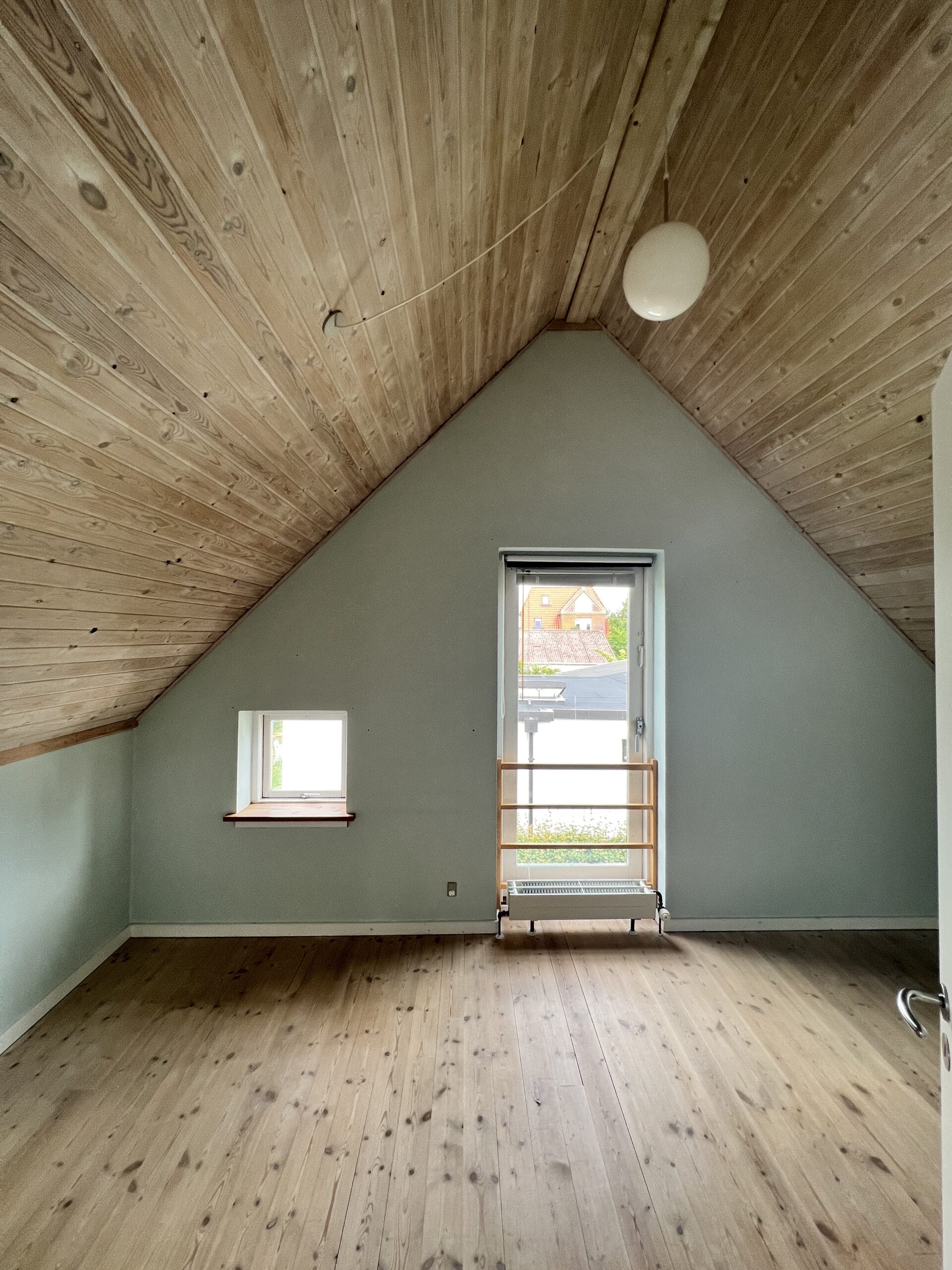Lyst loftværelse med trægulv og skrå loftvægge